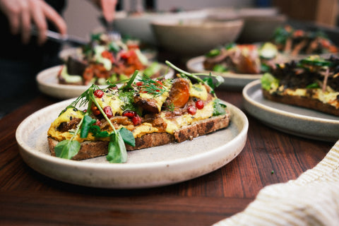 Een bord met broodje gele hummus en groenten