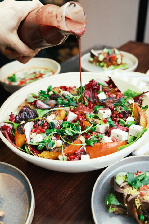 Een karafje met dressing wordt gegoten over een salade bowl